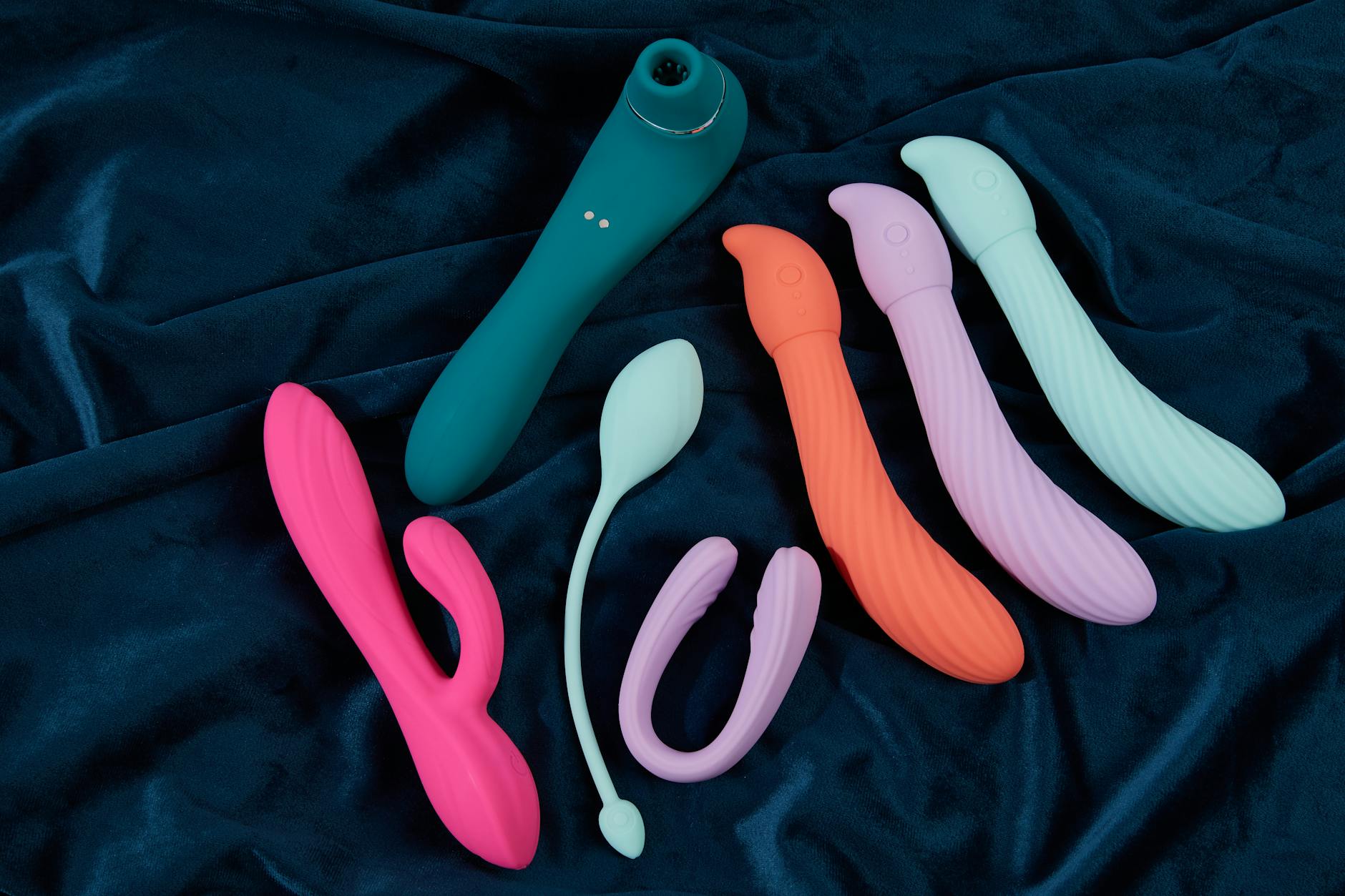 Vibradores coloridos dispostos em superfície amarela brilhante