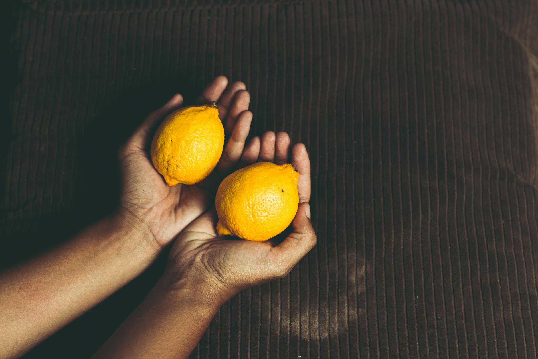 A close-up of a hand holding an orange vibrator against a minimalistic purple backdrop, showcasing modern sensuality.
