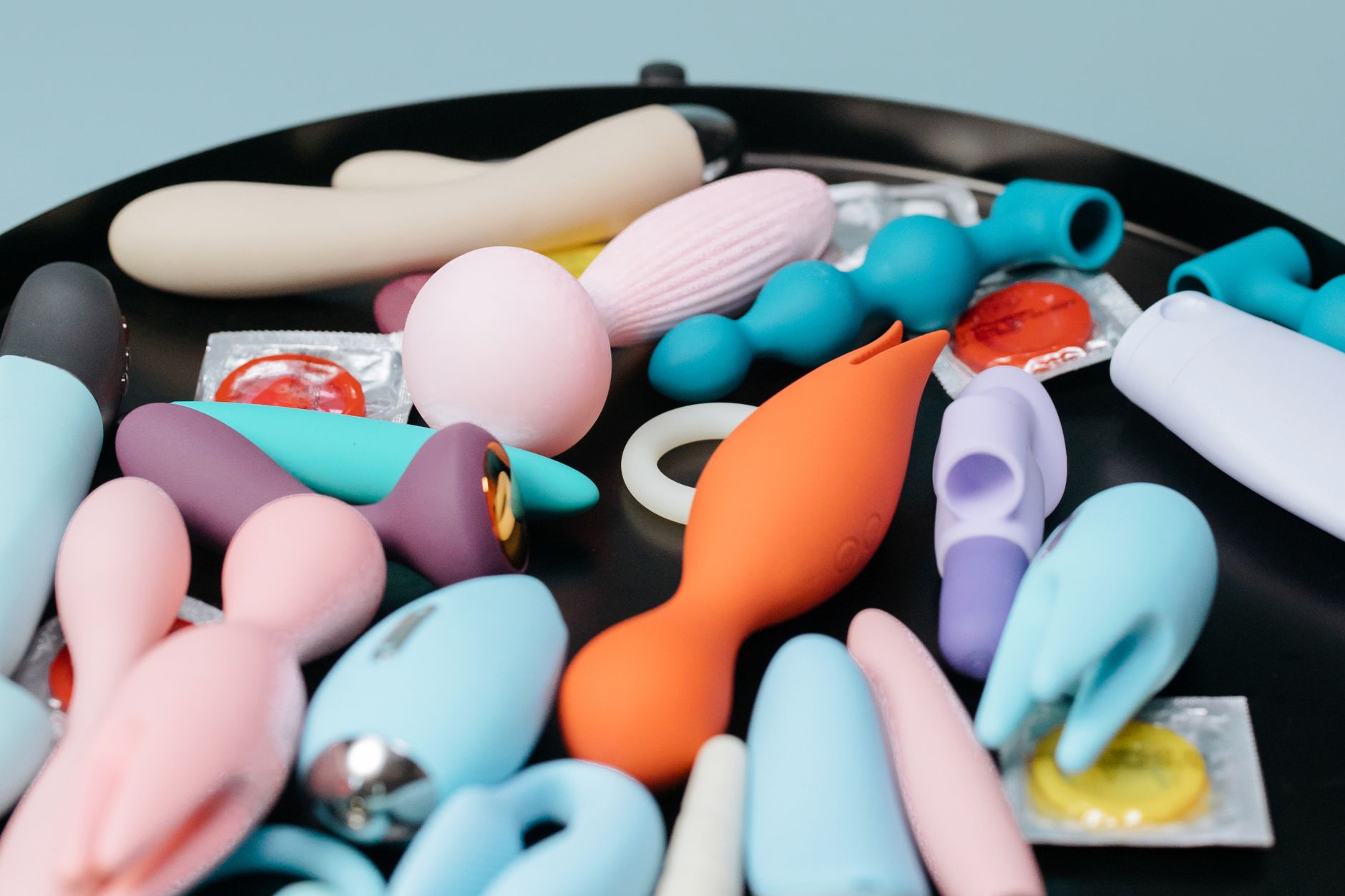 Woman holding blue and pink vibrators in a calm moment of self care