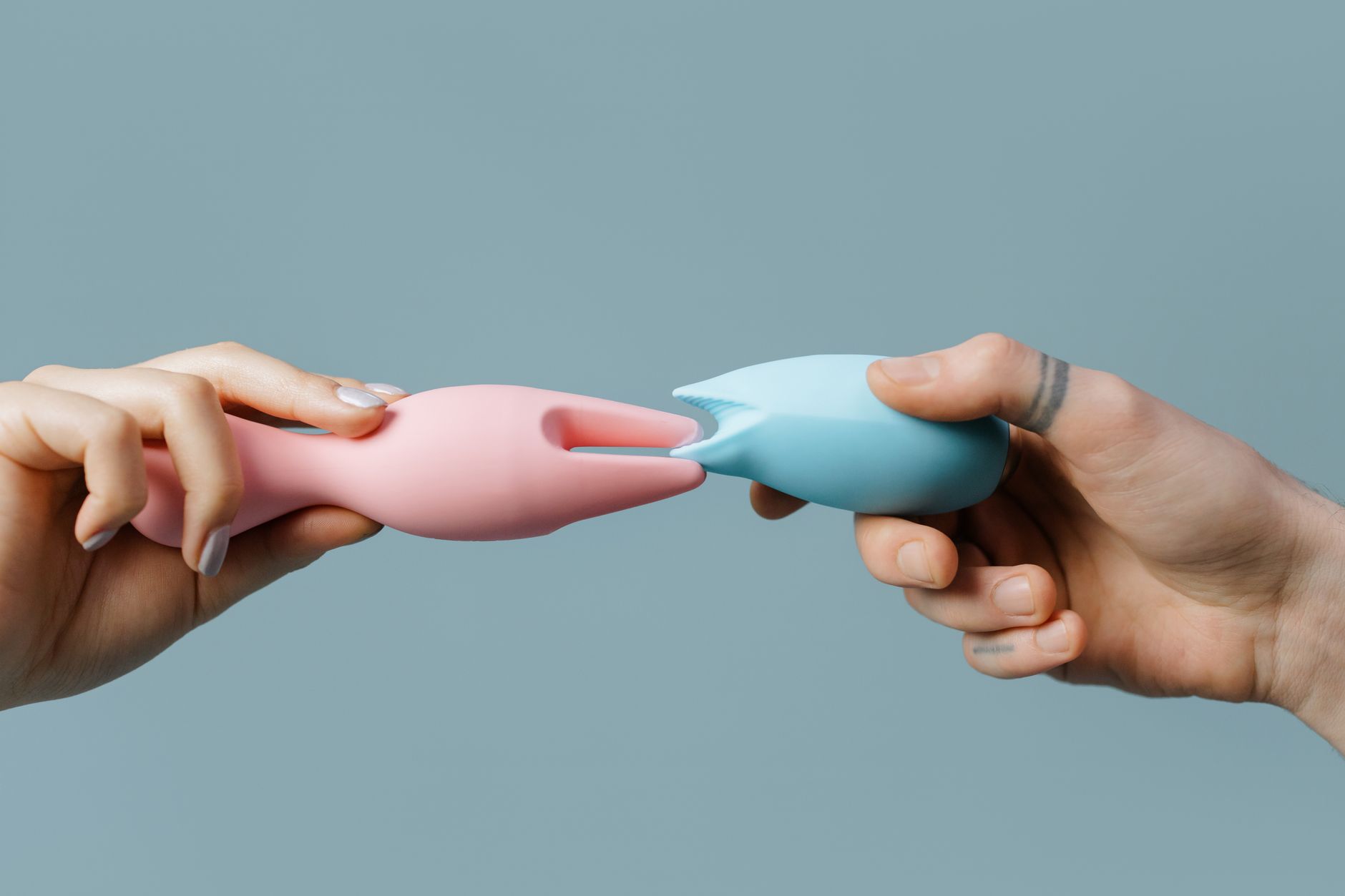 Mãos segurando um vibrador azul elegante contra fundo roxo, representando prazer solo e autoconhecimento