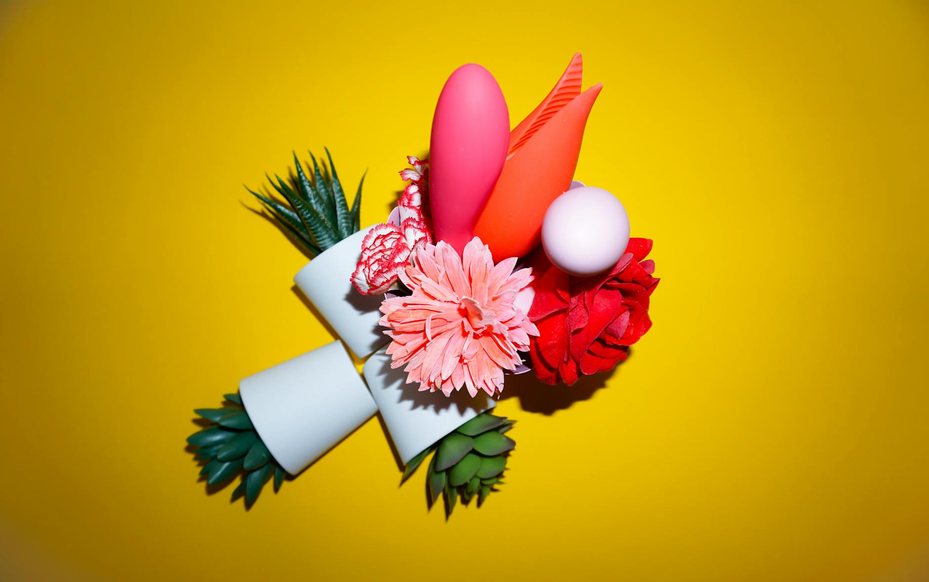 Studio display of colorful vibrators and adult toys on a bright yellow background