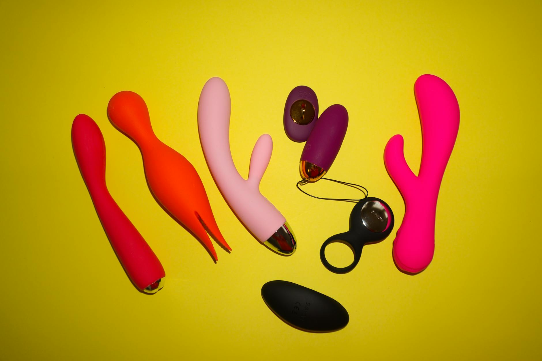 Colorful sex toys on a bright yellow background, representing diverse pleasure options