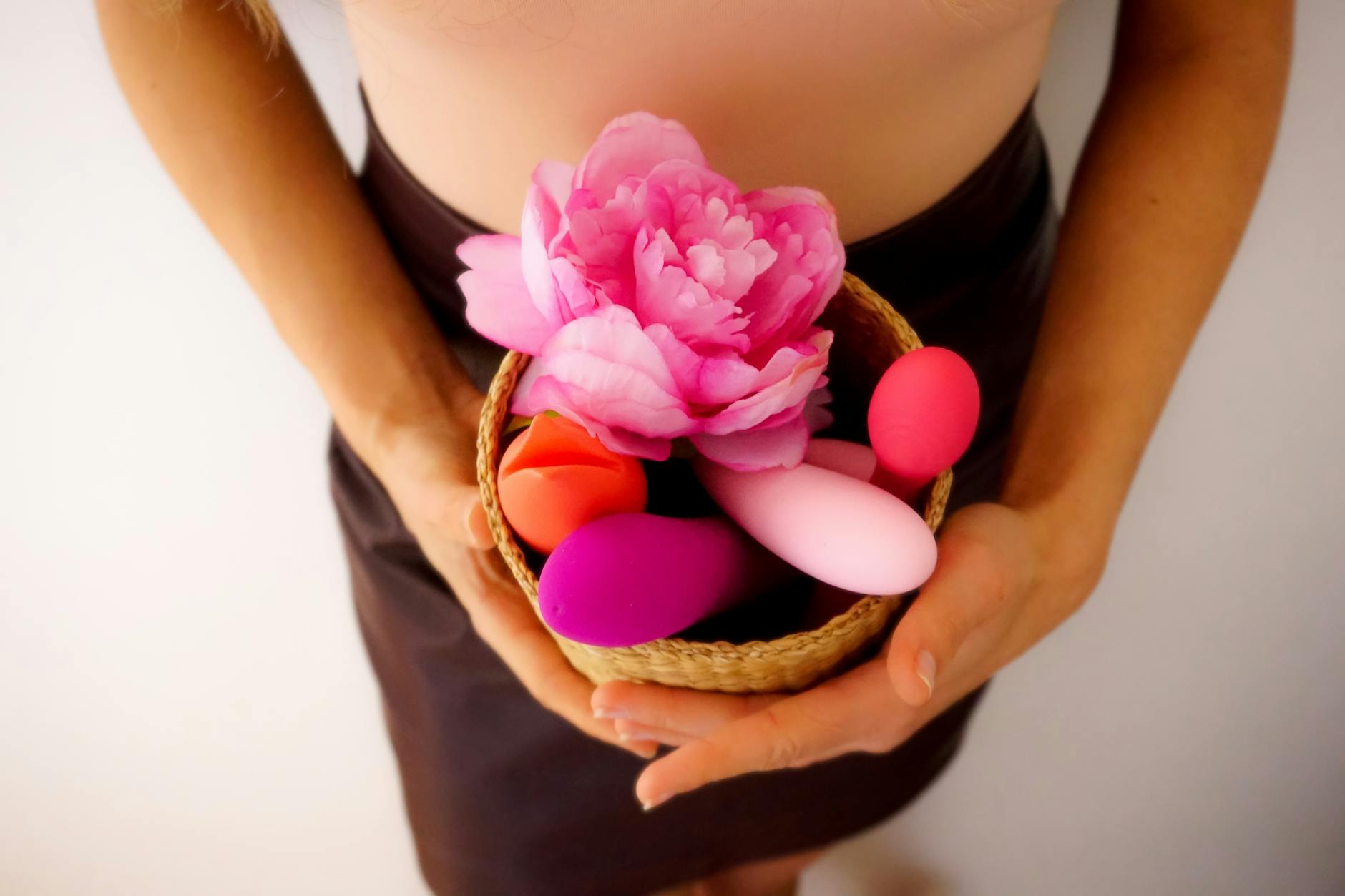 Woman holding a pink vibrator with art books nearby, representing intimate reconnection and personal pleasure